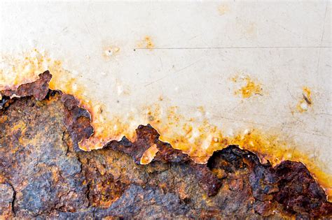 Primo piano di una piccola macchia di ruggine su un pannello di lamiera
