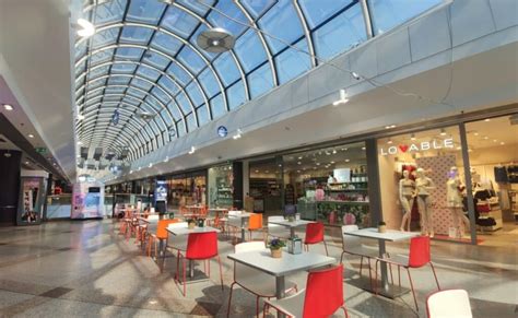 Esterno di un moderno centro commerciale con persone che entrano ed escono