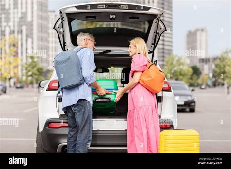 Coppia che carica il bagagliaio dell'auto con valigie e oggetti per un viaggio