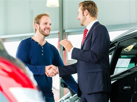 Concessionaria auto moderna con venditore che interagisce con un cliente davanti a un veicolo elettrico