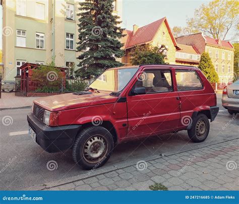Una Fiat Panda parcheggiata in un parco nazionale africano con animali selvatici sullo sfondo.