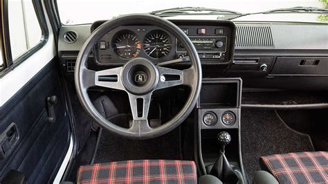 Interni della Volkswagen Golf GTI Mk1 con sedili in tessuto tartan e pomello del cambio a forma di pallina da golf