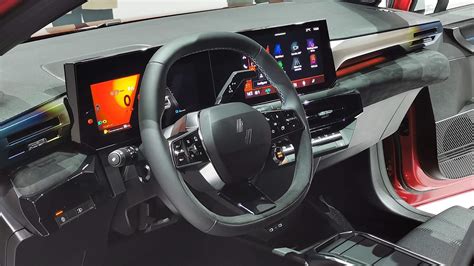 Interni di un'auto con volante e display digitale. Il display centrale mostra il controllo delle luci digitali e informazioni sulla temperatura.