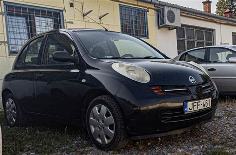 Una strada di città con una Nissan Micra K12 parcheggiata