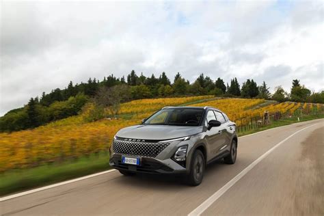 Veicolo SUV grigio in movimento su strada urbana con edifici moderni sullo sfondo