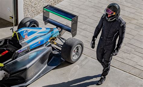 Pilota in tuta da gara accanto a una vettura da competizione