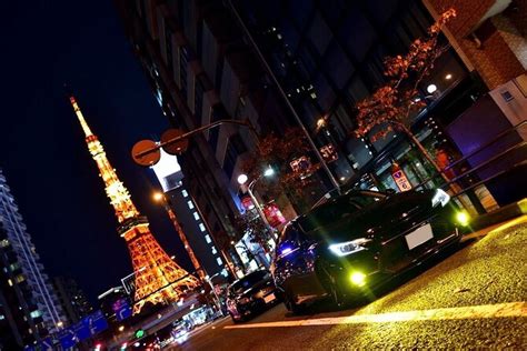Veduta notturna di Tokyo con auto sportive in movimento