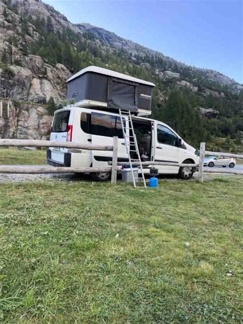 Veicoli con tende da tetto parcheggiati in un'area sosta in un ambiente naturale