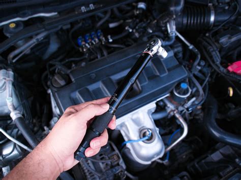 Meccanico che lavora sotto un'auto, con una chiave dinamometrica per serrare un componente della sospensione.