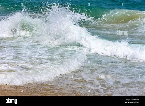 Onda che si infrange sulla spiaggia con spuma