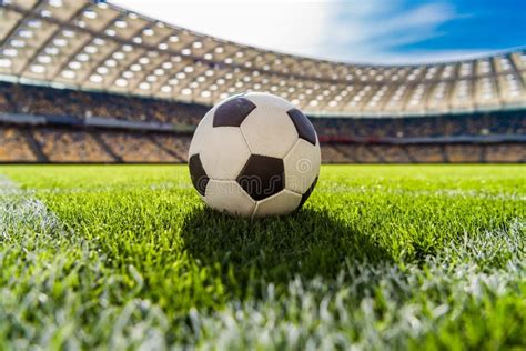Calcio con pallone in primo piano e stadio sullo sfondo