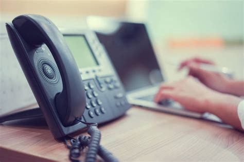 Persona che risponde al telefono con la cornetta di un telefono fisso antico
