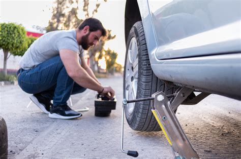 Persona che cambia una ruota in sicurezza a lato della strada