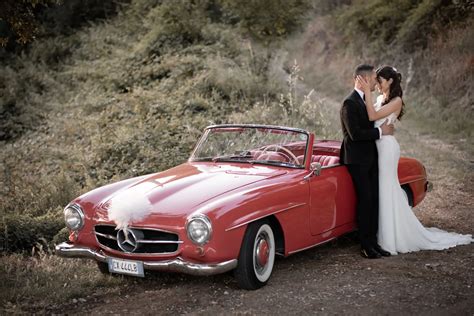 Coppia di sposi che sale su un'auto d'epoca decorata per matrimonio