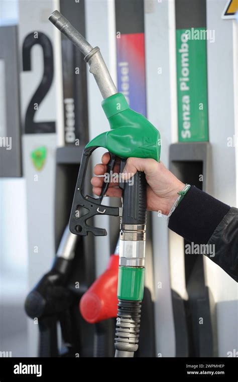 Automobilista con pistola benzina inserita che si allontana dal distributore