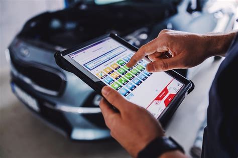 Person viewing a digital manual on a tablet next to a car engine