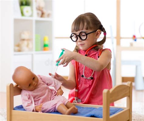 Bambina che gioca con una bambola Corolle e lo spazzolino