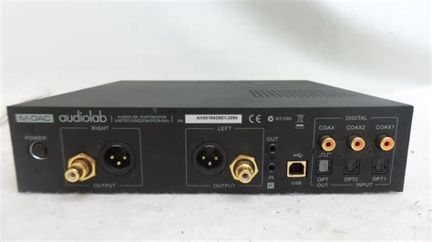 Un DAC Audiolab in primo piano con cuffie