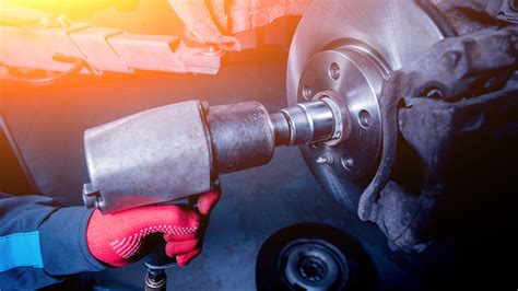 Meccanico che utilizza una chiave a impulsi pneumatica per rimuovere un bullone di una ruota d'auto