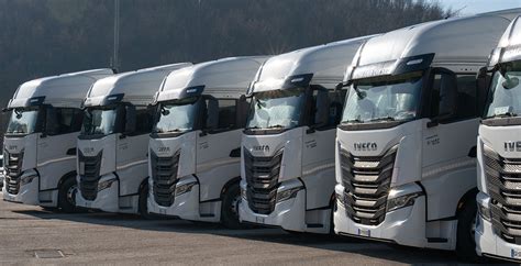 Flotta di camion telonati su un'autostrada ventosa