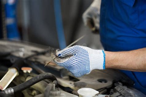 Meccanico che controlla l'olio motore con l'astina