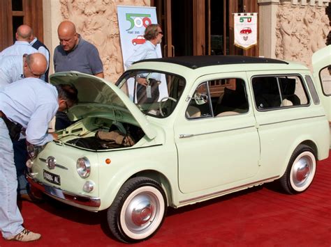 Logo storico Fiat con sfondo sfocato di veicoli d'epoca