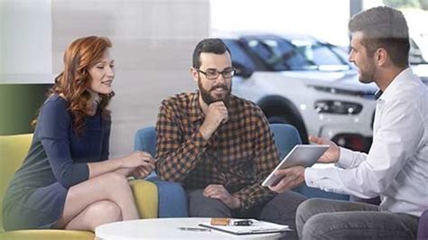 Concessionaria auto con consulente che mostra opzioni di finanziamento al cliente