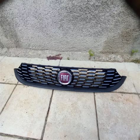 Dettaglio ravvicinato della calandra anteriore e del logo Fiat 500 L su uno sfondo di officina specializzata