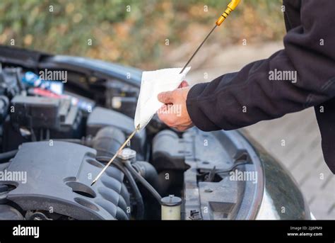 Automobilista che controlla il livello dell'olio motore con l'astina