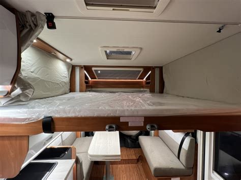 Interno di un Fiat Doblò trasformato in camper con letto e zona cucina