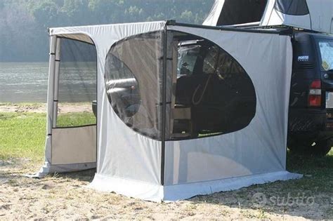 Un 4x4 con tendalino laterale aperto e un tavolo e sedie da campeggio sotto di esso