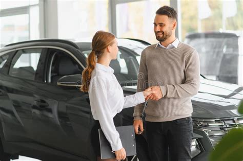 Happy customer shaking hands with a car salesman