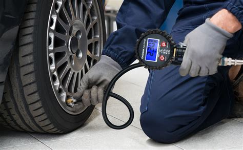 Un gommista che controlla la pressione di uno pneumatico con un manometro digitale