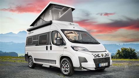 Veduta frontale di un camper mansardato basato su meccanica Fiat Ducato in un paesaggio montano
