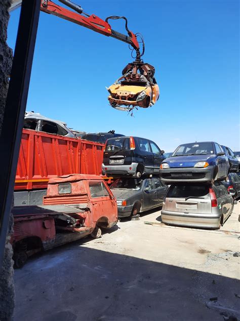 Un centro di autodemolizione con veicoli accatastati e attrezzature per il recupero