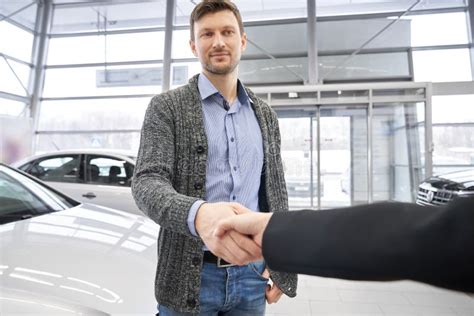 Uomo sorridente che saluta il cliente in una concessionaria di auto