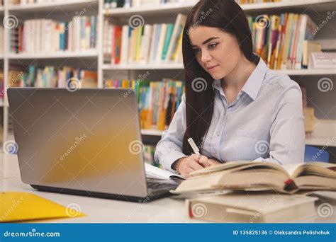 Studentessa che lavora alla tesi con libri e computer